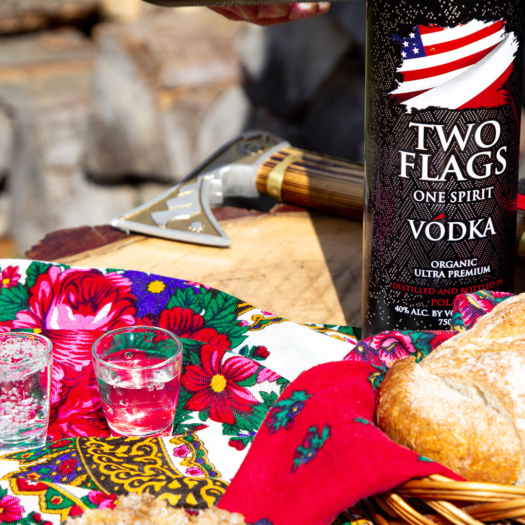Two Flags One Spirit Vodka bottle on a vibrant table setting with shot glasses and bread. Ultra-Premium Organic Vodka